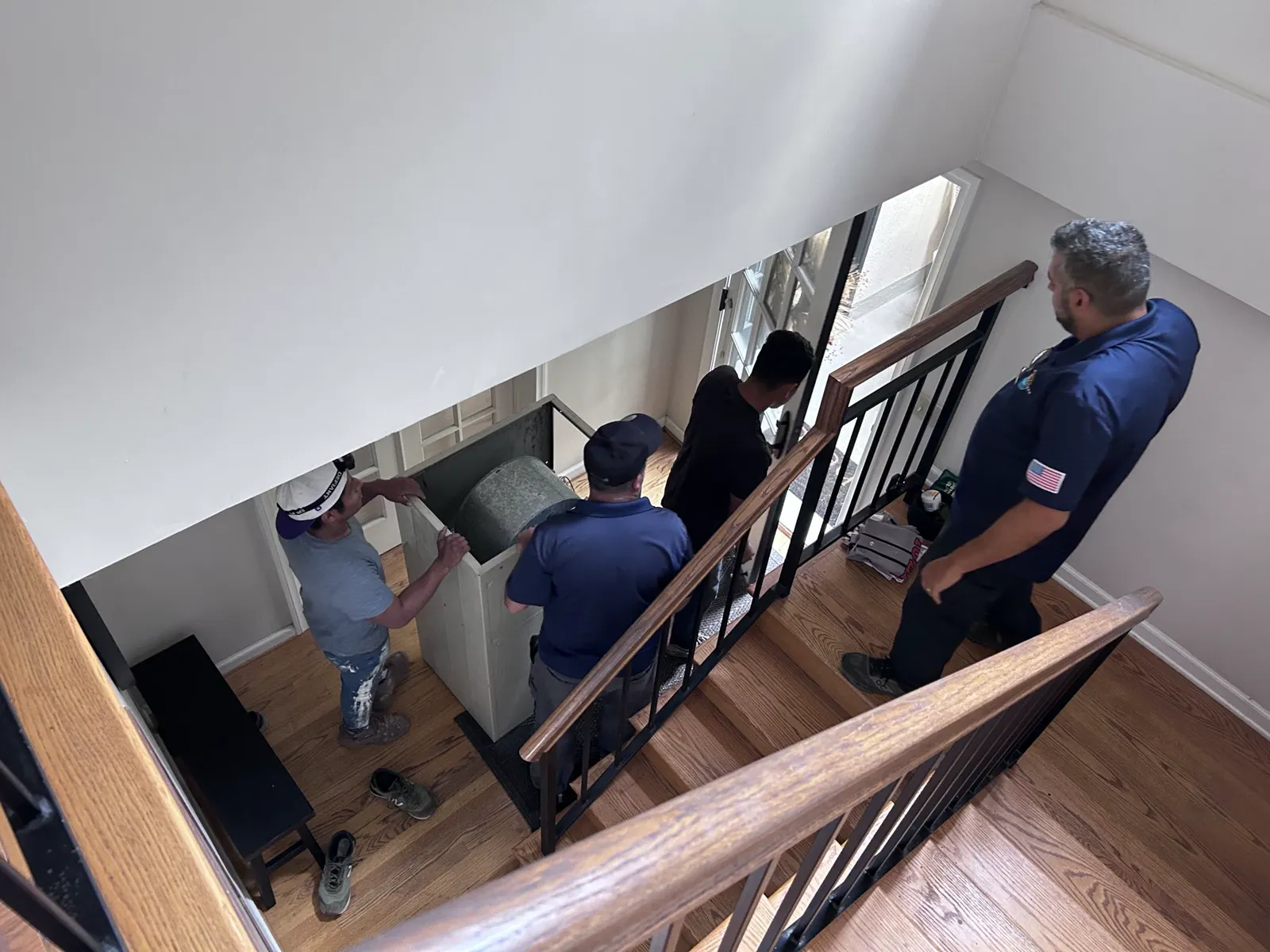 Boost crew carrying an air handler down a staircase