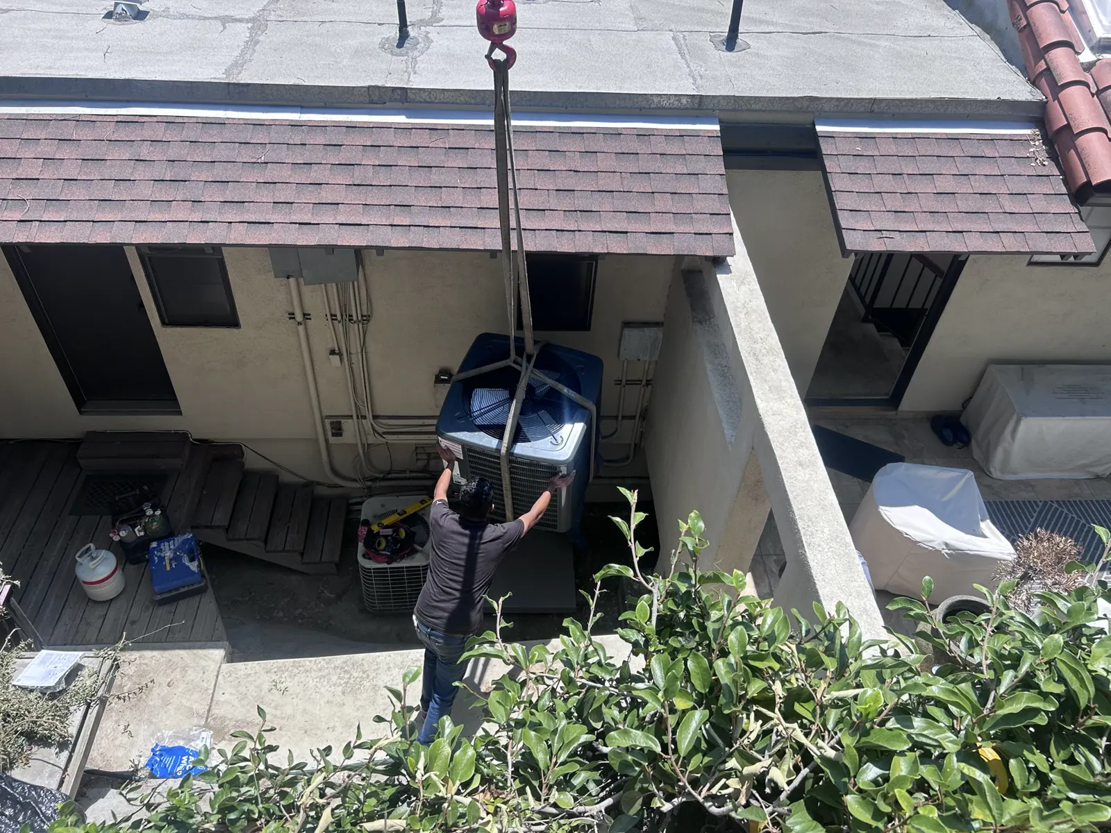 A new condenser being craned over a house