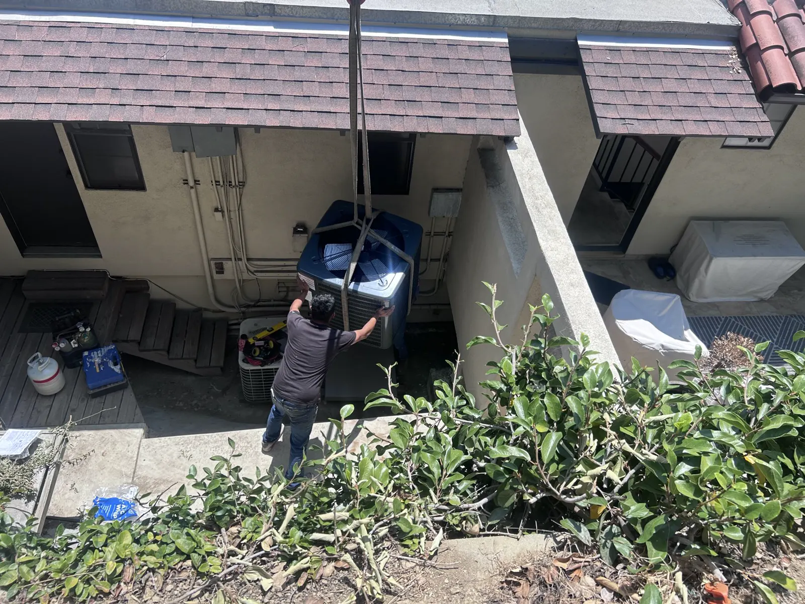 Crane lowering a condenser into a side yard