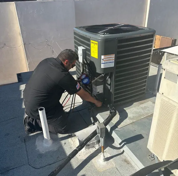 Boost technician checking gauges on a rooftop condenser