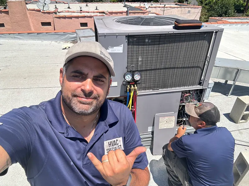 Two Boost technicians servicing a rooftop unit, gauges connected