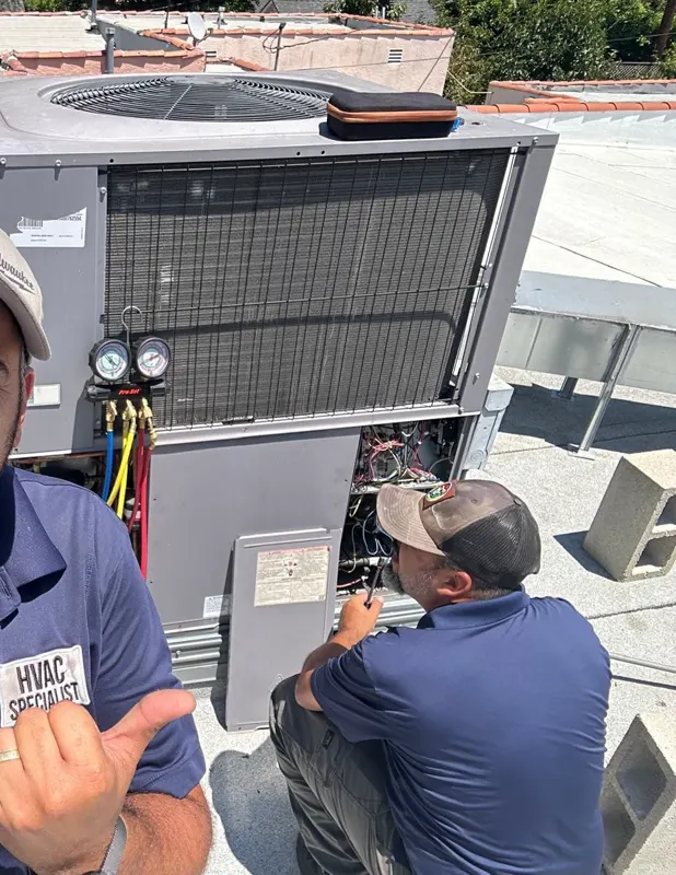 A Boost technician with gauges connected to a rooftop unit during a maintenance visit