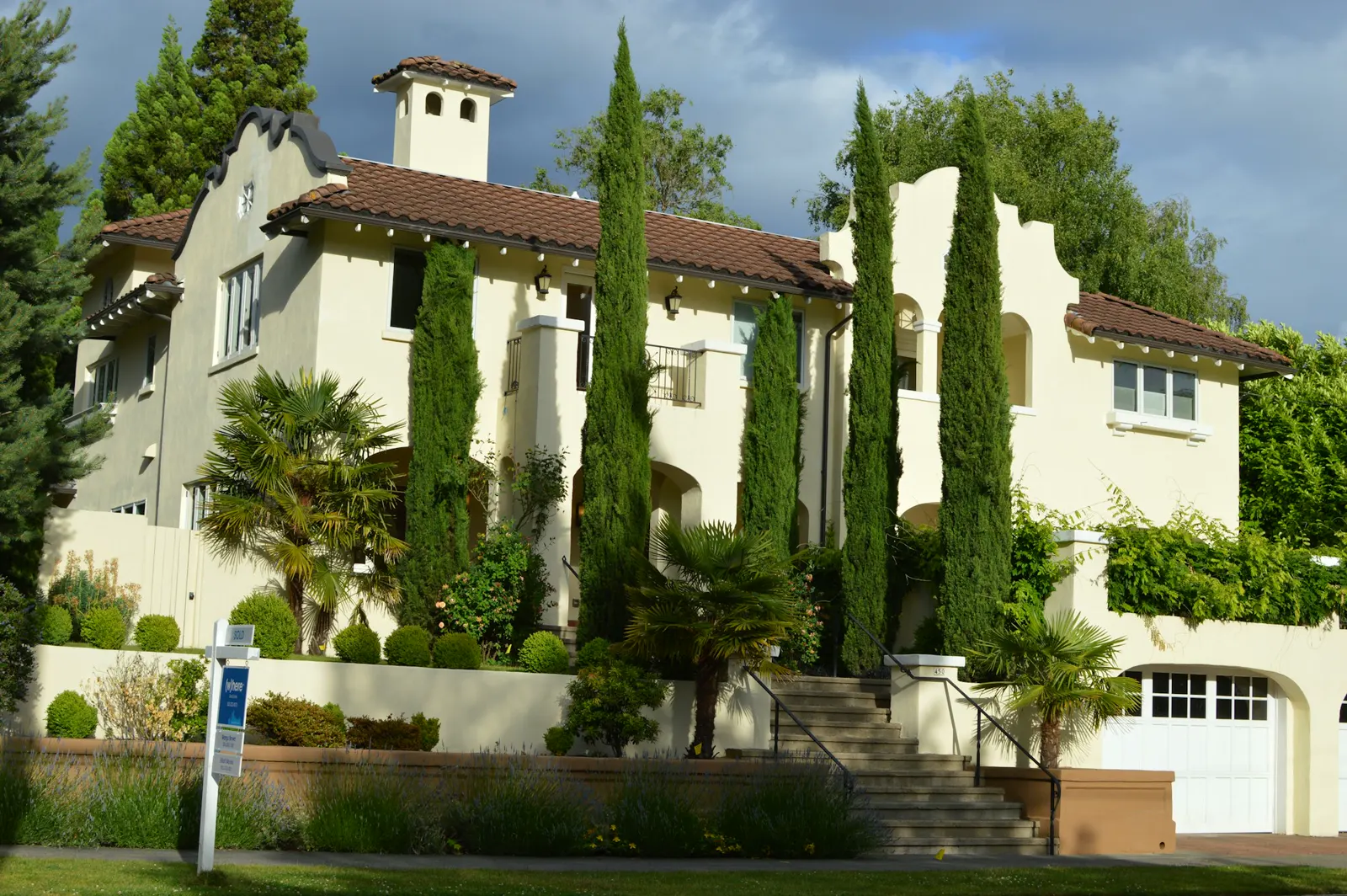 Elegant house with tall cypress trees and a white garage