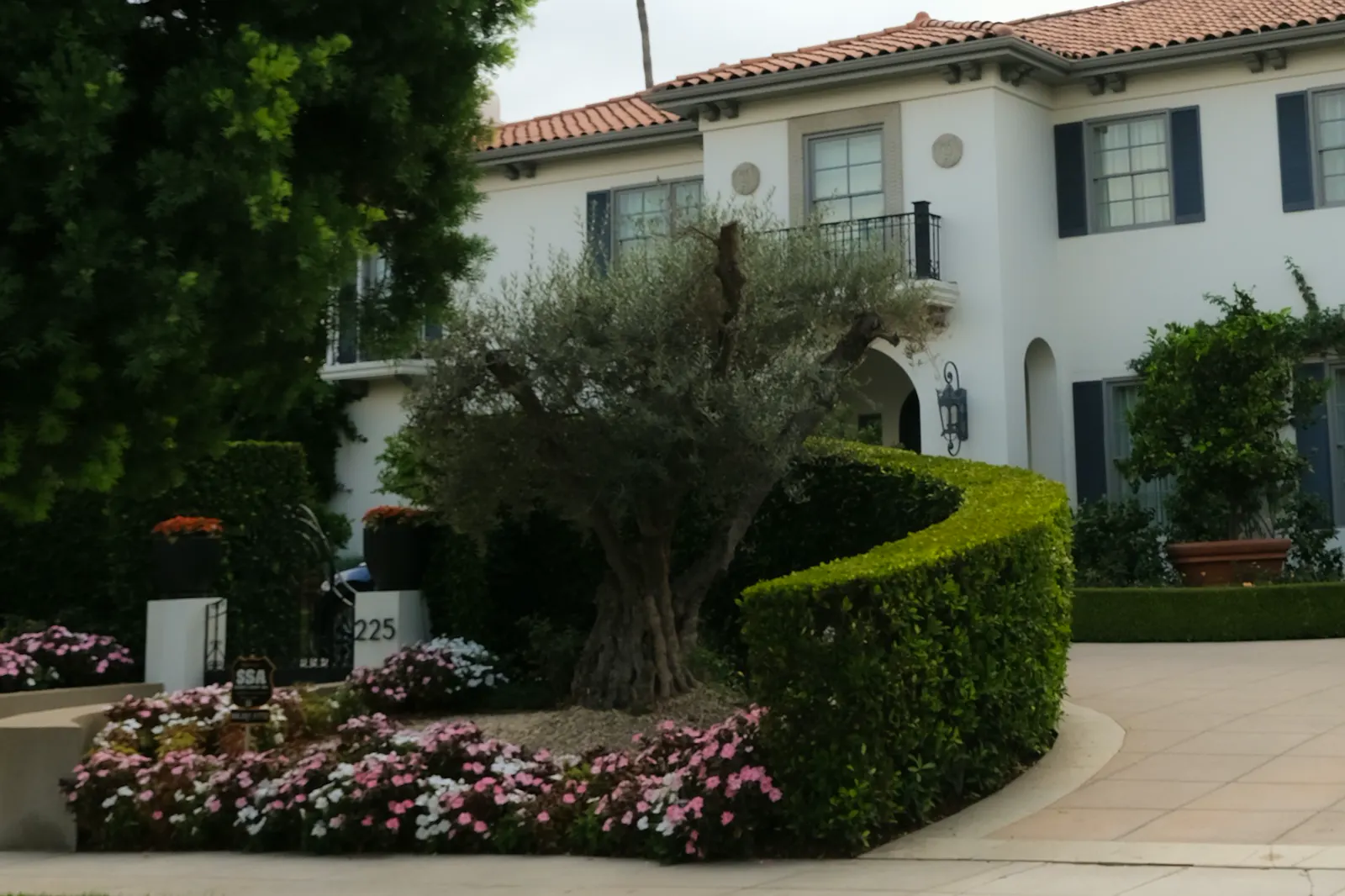 White mansion with manicured hedges and flowers