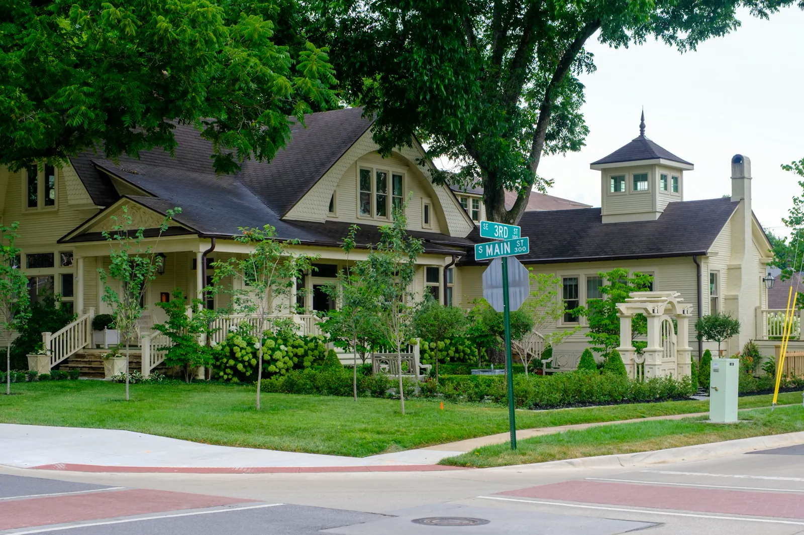 A charming yellow house with a porch and garden