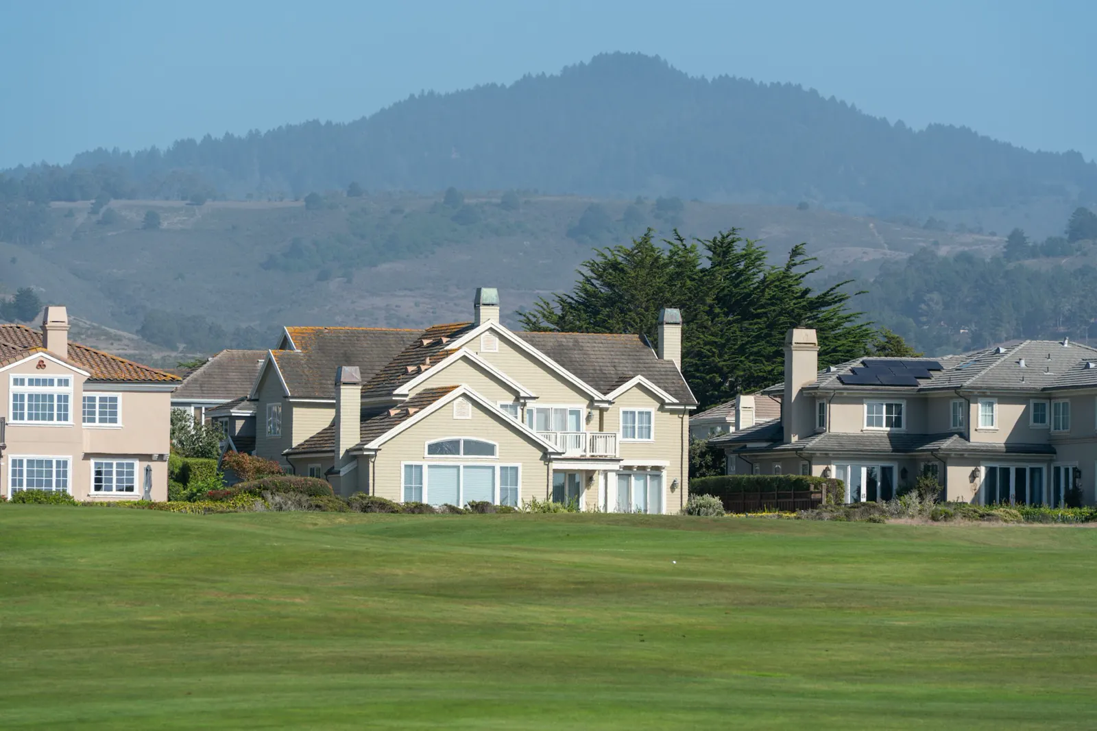 Suburban houses on a green lawn with hills behind