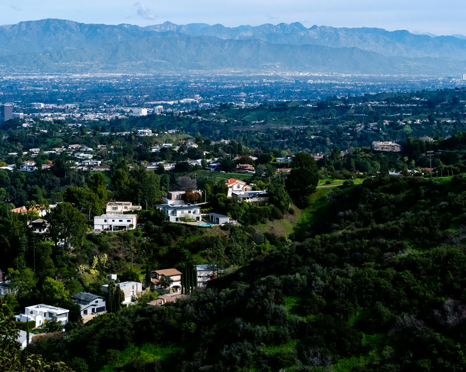 Suburban homes nestled in rolling green hills with mountains beyond