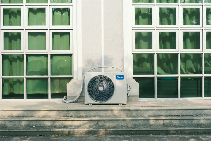 A ductless outdoor unit installed below a row of windows
