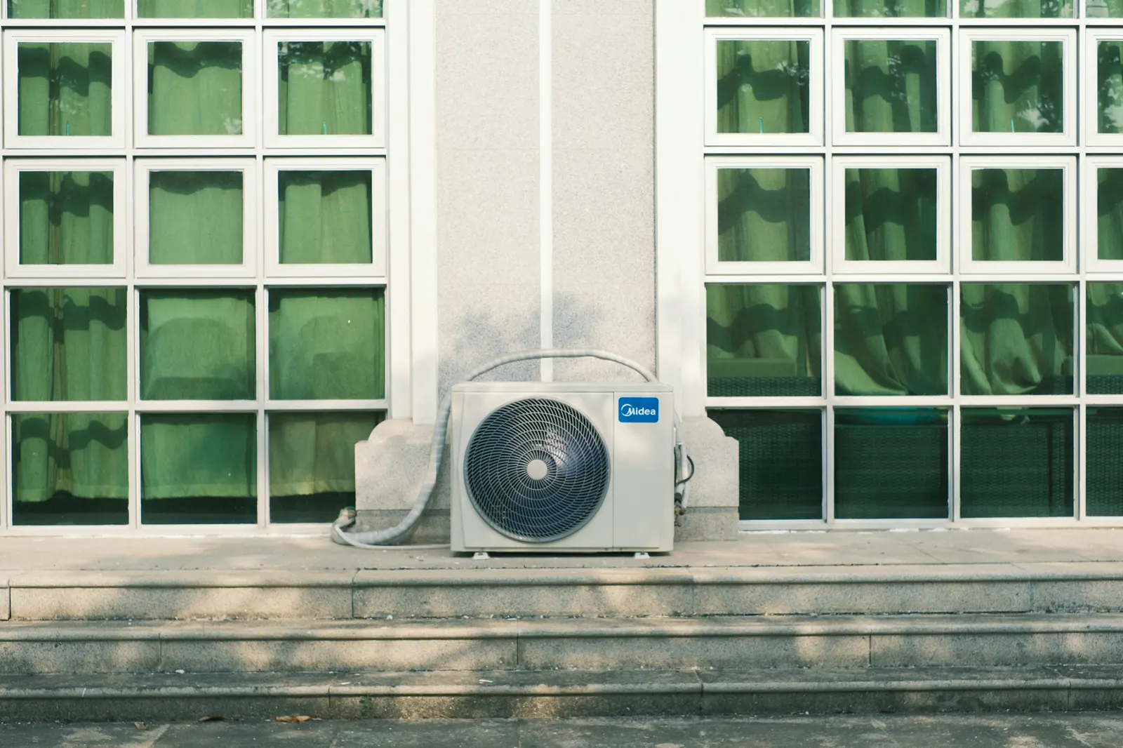 A ductless outdoor unit installed below a row of windows
