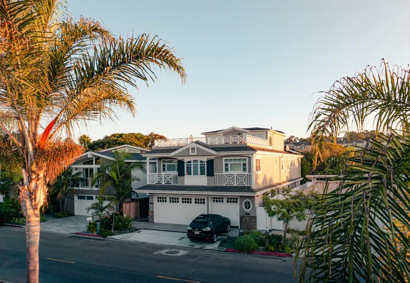 A two-story home framed by palm trees