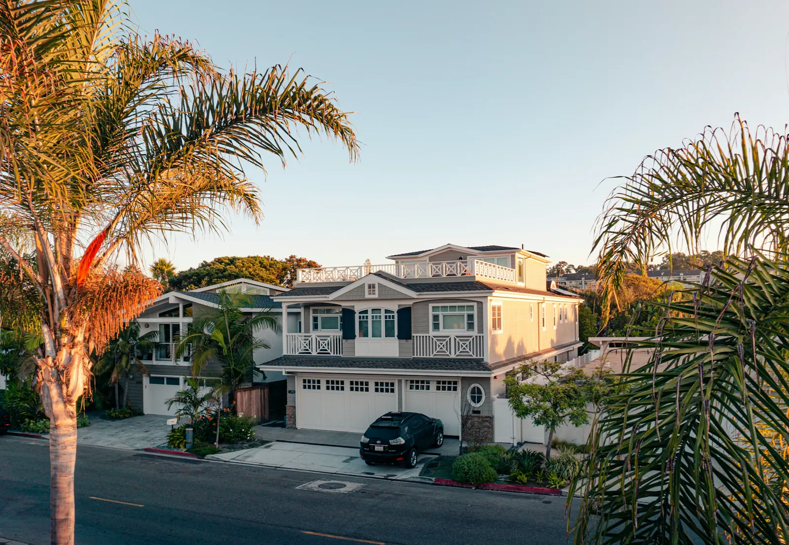 A two-story home framed by palm trees