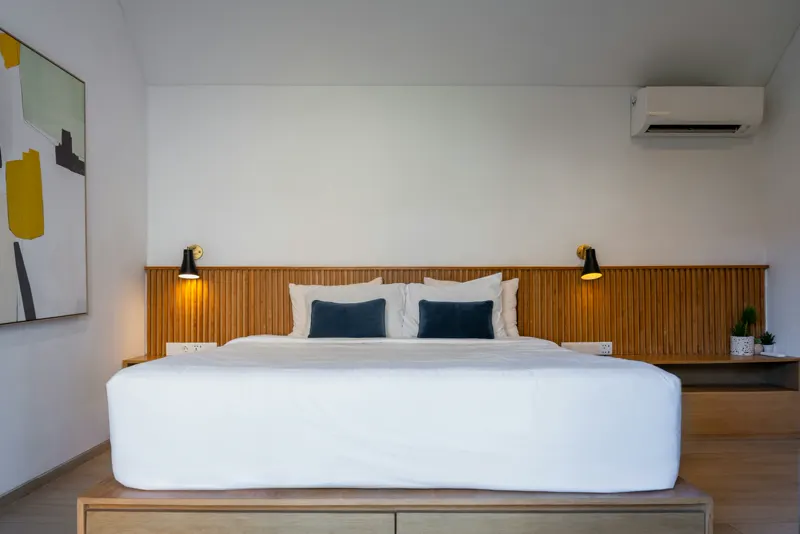 A wall-mounted mini split in a bedroom with wood panelling