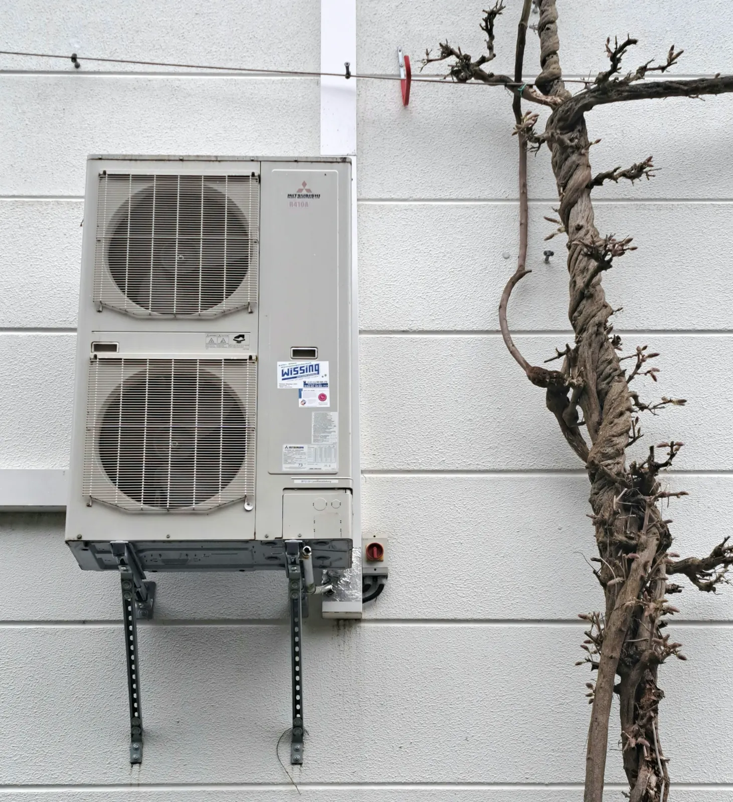 A two-fan ductless outdoor unit mounted on a wall bracket