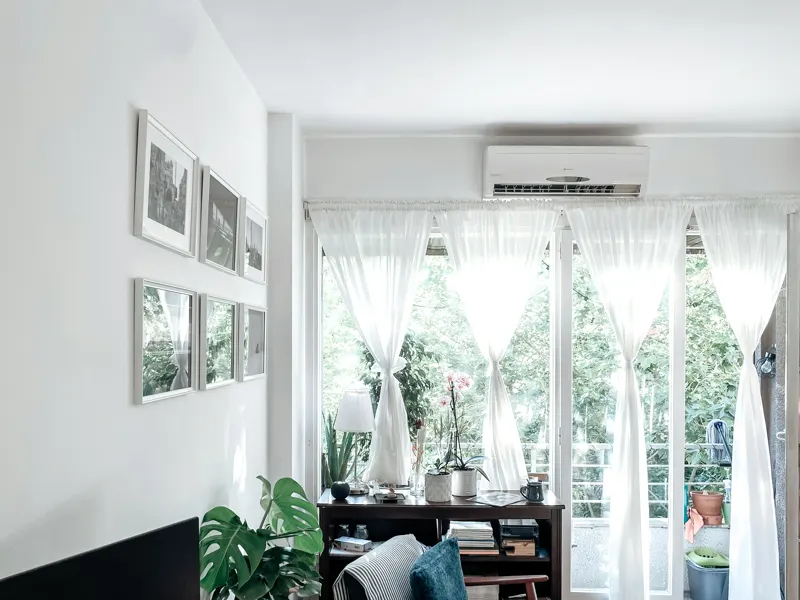 A ductless mini split head mounted above a bright window
