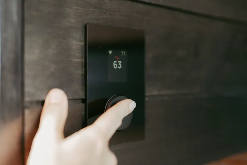 A hand adjusting a wall thermostat