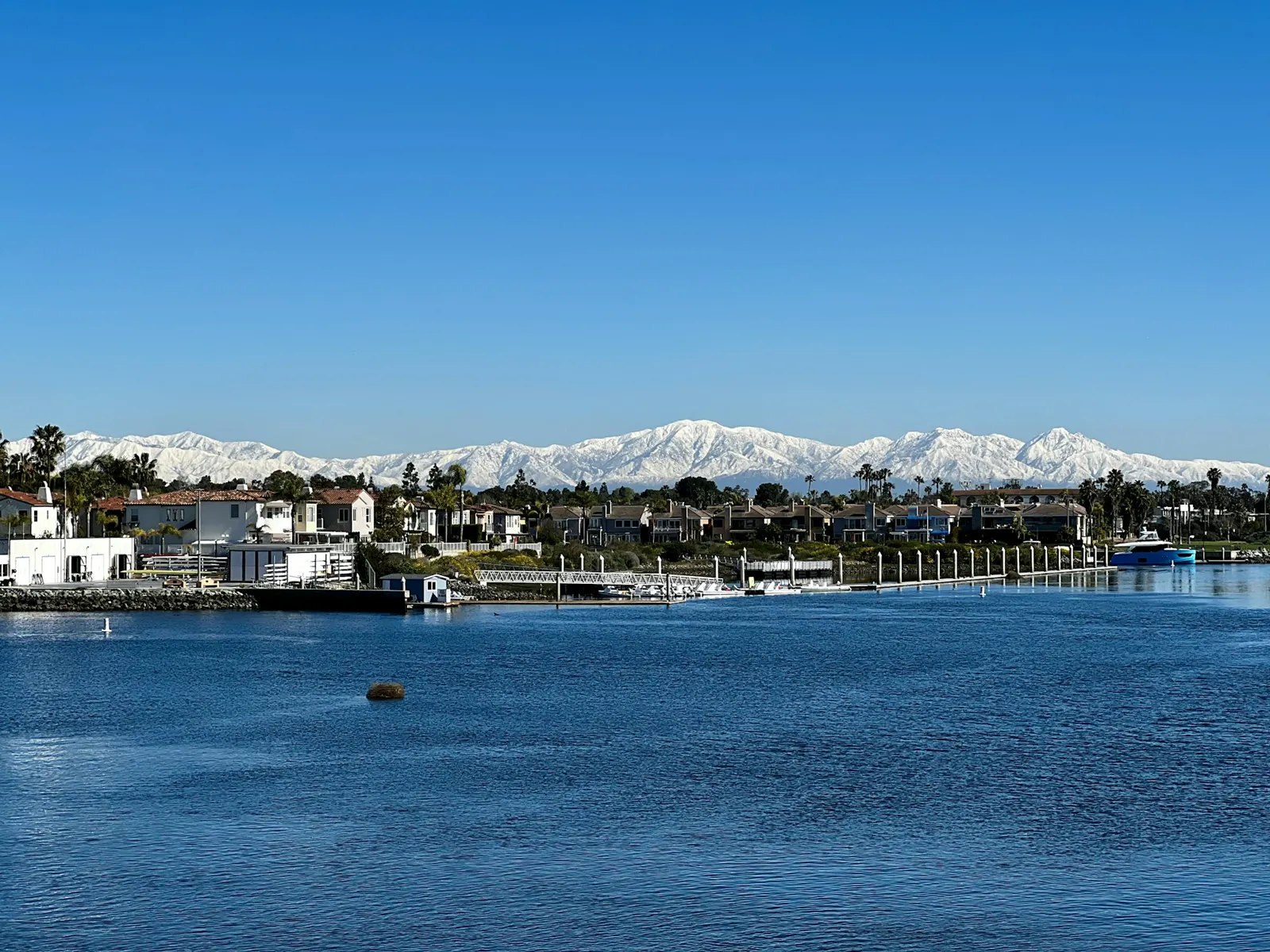 Homes along the water below snow-capped mountains