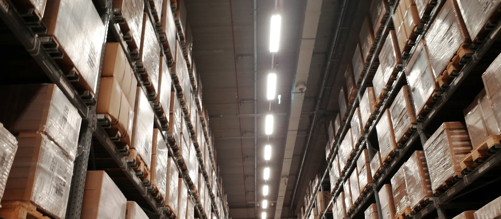 Looking up a warehouse aisle of tall racking stacked with boxes