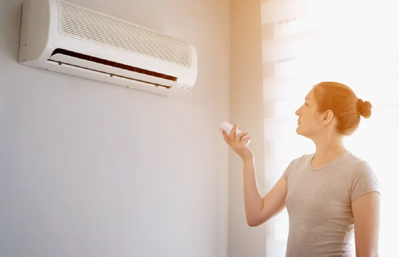 A hand held up to a wall air conditioner vent to feel the air