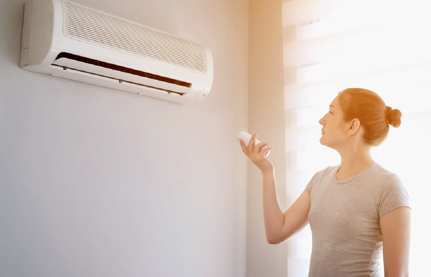 A hand held up to a wall air conditioner vent to feel the air