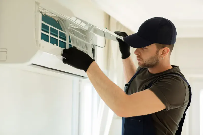 Technician in gloves opening the cover of a wall-mounted indoor air conditioning unit