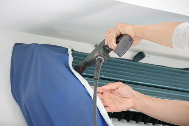 Technician rinsing the fins of an outdoor condenser coil