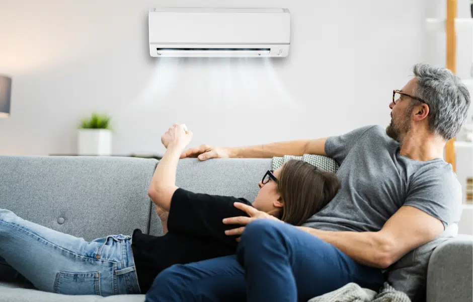 A man and a woman are sitting in a room with an air conditioner.